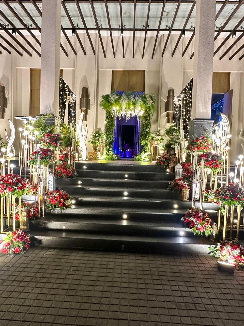 Grand night entrance staircase lined with red flowers and lights